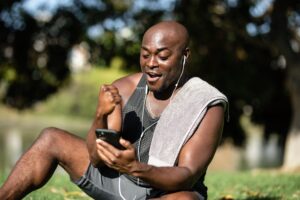 Smiling man outdoors celebrating with smartphone after exercise.