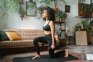 African woman working out indoors with dumbbells and yoga mat. Home fitness lifestyle.